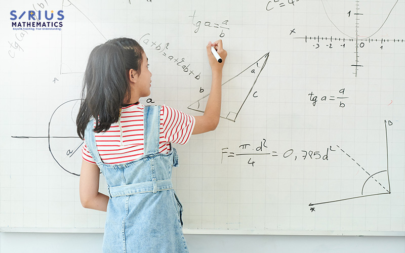 Student solving math problems on a whiteboard.