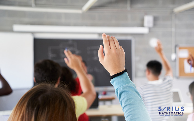 Students raising hands in a math class.