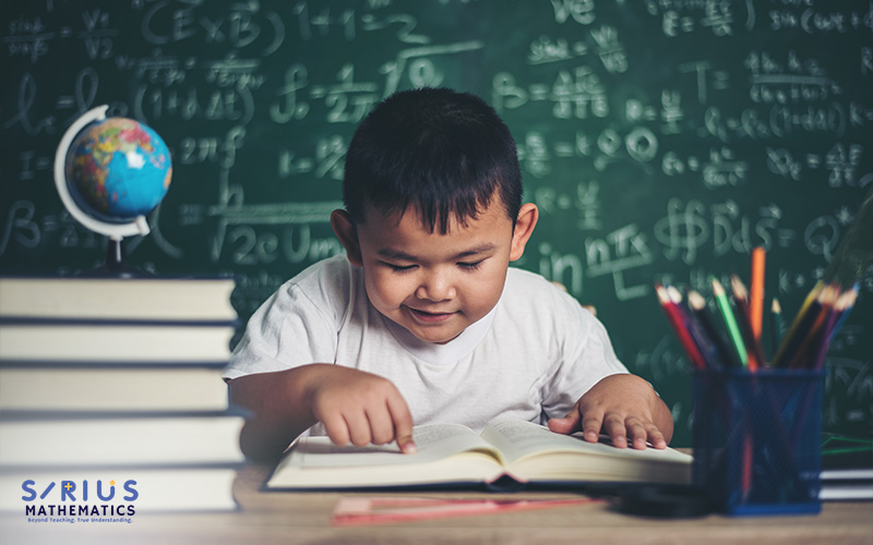 Young boy happily studying math with books. 