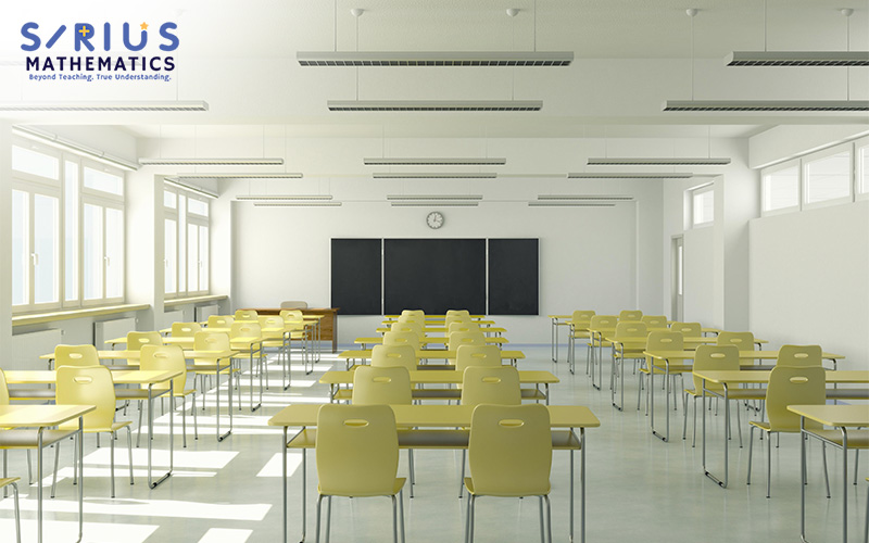 An empty classroom with desks, chairs, and a chalkboard.