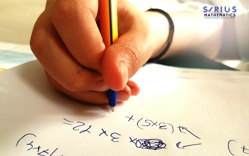 Hand writing out complex A-Maths equations.