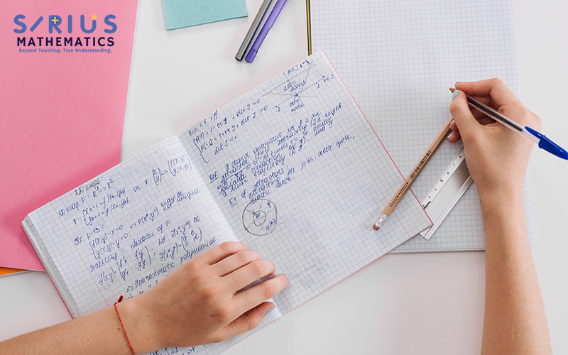 Student planning complex A-Maths problems in a notebook.