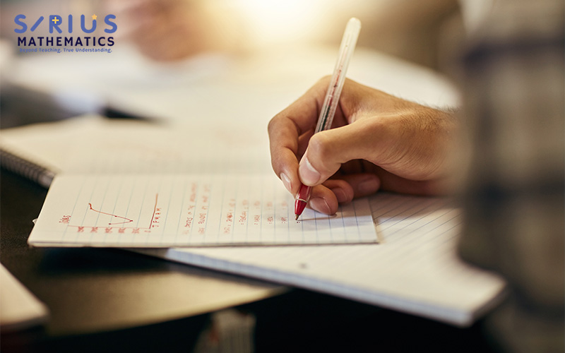 Person marking completed math exercises with red checkmarks in a notebook featuring a geometric diagram.