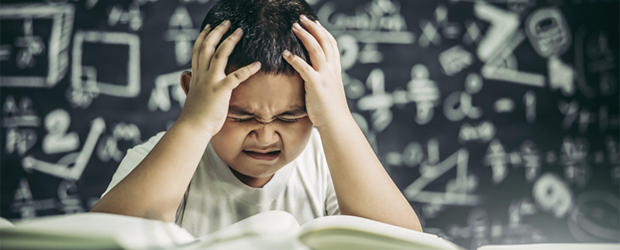 Student struggling with math equations on chalkboard.
